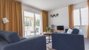 A modern living room with two sofas, a TV, and a table with decorative items. - Terrace Stay near Shoreline (Berck-Sur-Mer)