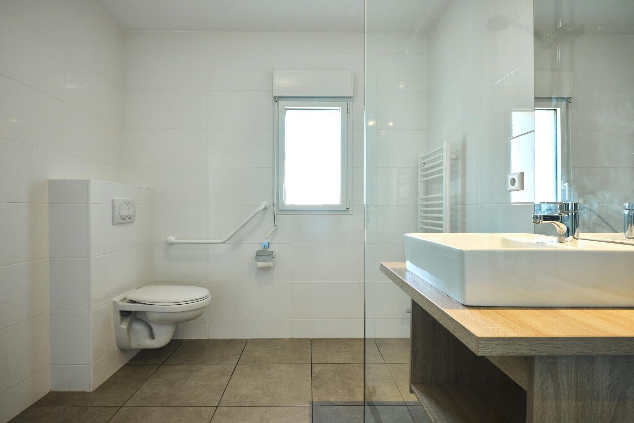 A modern bathroom with a toilet, a sink, and a glass shower enclosure.