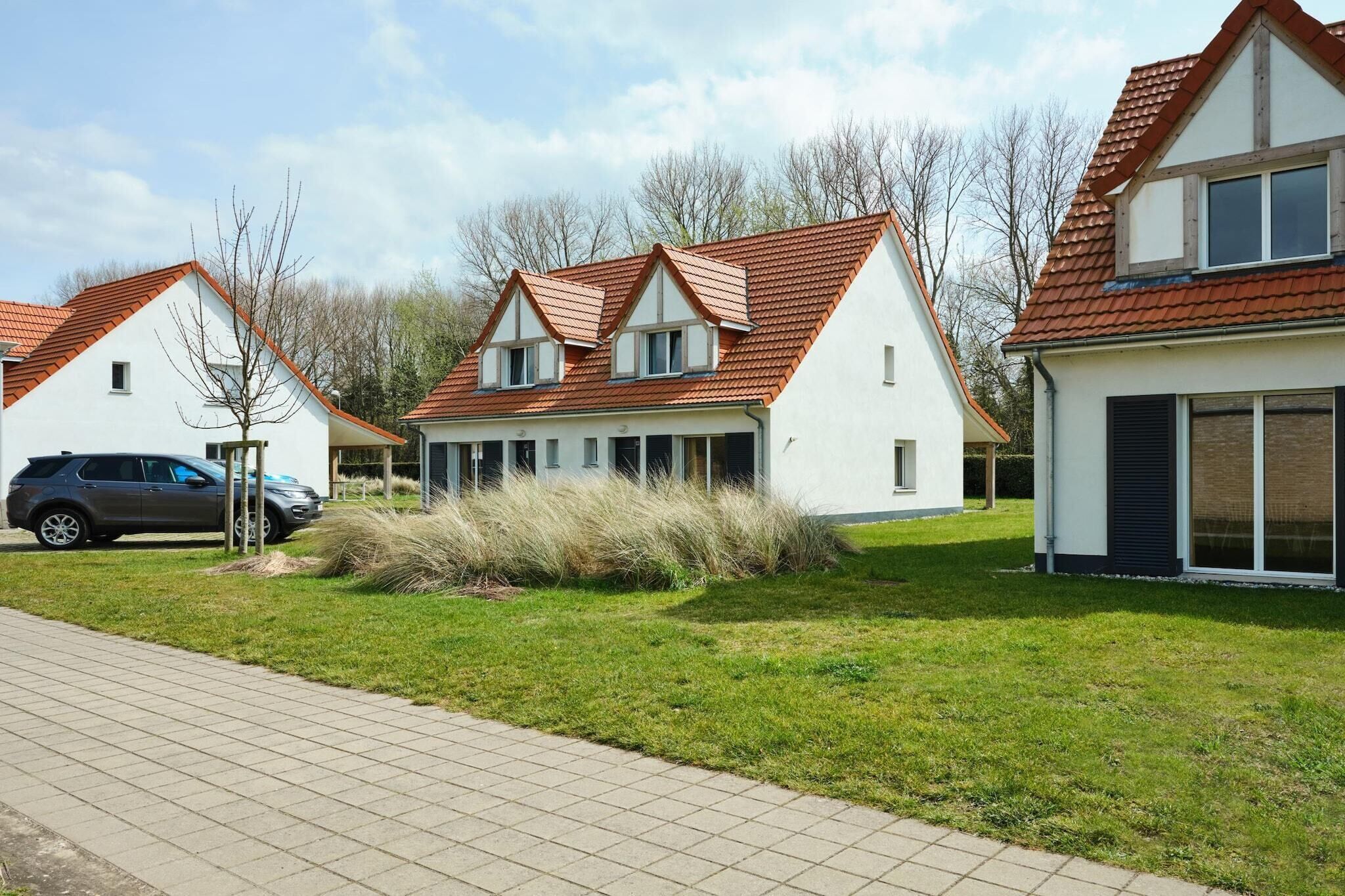A modern residential area with detached houses featuring red-tiled roofs and white exteriors.