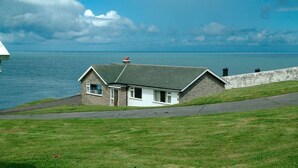 Een huis aan de kust met een stenen gevel, een zadeldak en uitzicht op zee.