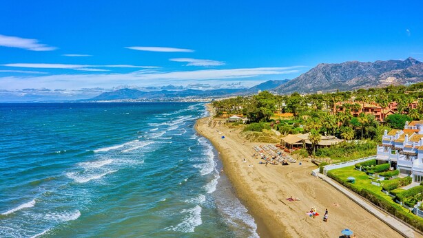 A coastal beach with a view of mountains in the background.
