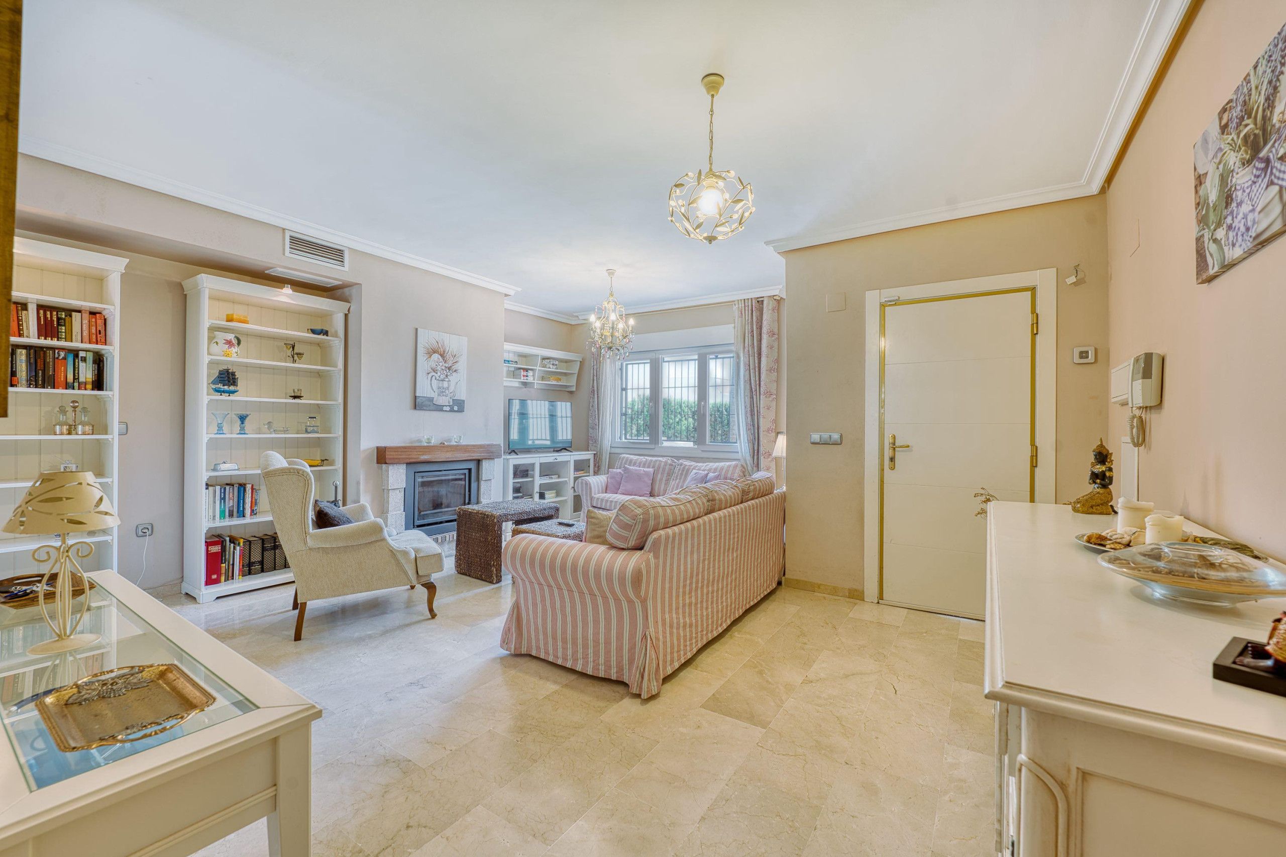 A spacious living room with a sofa, armchairs, a fireplace, and a chandelier.