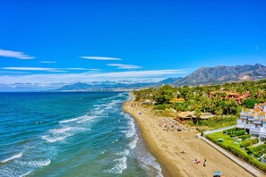 Uma praia costeira com vista para montanhas ao fundo.