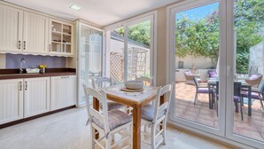 A kitchen with white cabinets, a dining table with chairs, and a view of a patio with outdoor furniture.