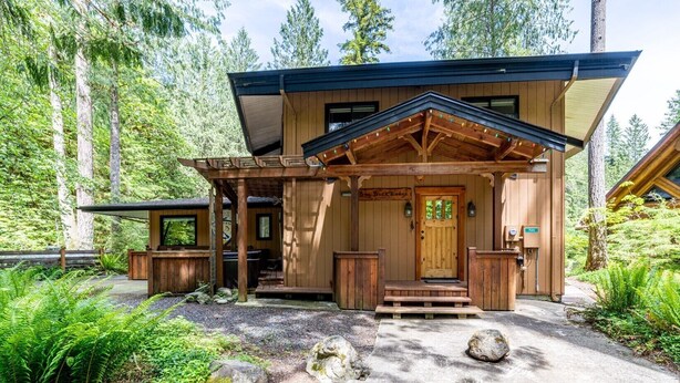 A wooden lodge with a covered porch, a front door, and a sign reading "Big Buck's Lodge." - Swimming pool, pickleball, tennis, basketball courts, private hot  tub, sauna. (Glacier)
