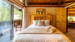 A bedroom with a large bed, wooden headboard, and a view of a deck. - Swimming pool, pickleball, tennis, basketball courts, private hot  tub, sauna. (Glacier)