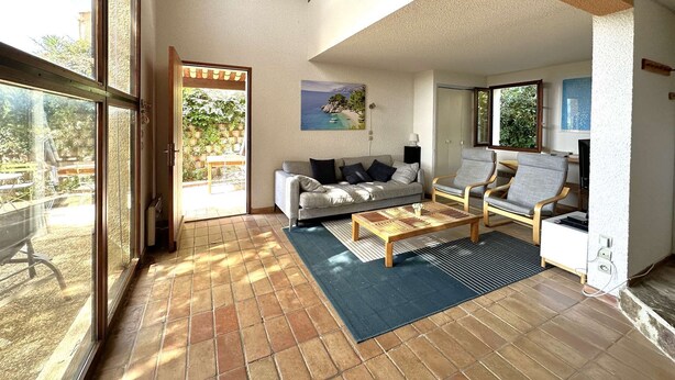 Un vaste espace de vie comprenant un canapé, deux fauteuils, une table basse et un tableau au mur.