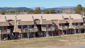A row of motel buildings with multiple balconies and a mountainous backdrop.