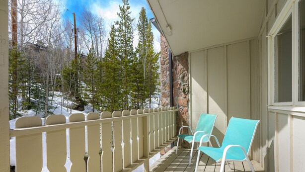 Een houten terras met twee stoelen en een witte reling.
