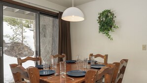 Een eettafel gedekt met borden, glazen en bestek, omringd door houten stoelen.