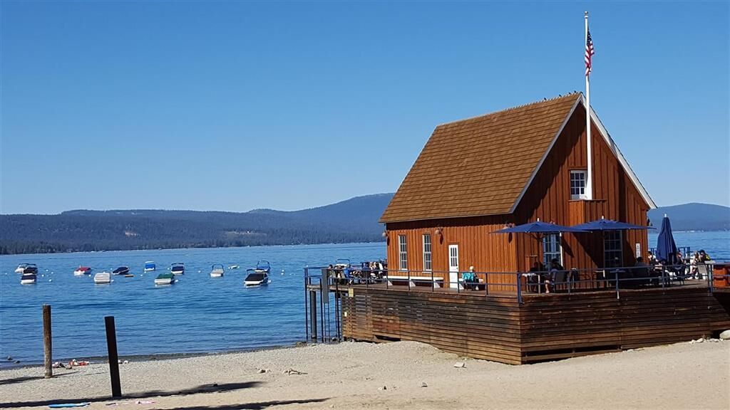 A wooden building with a sloped roof near a body of water, surrounded by boats.