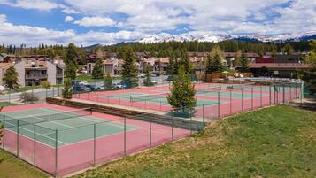 Tennis courts surrounded by mountain views and residential community in a scenic alpine setting.
