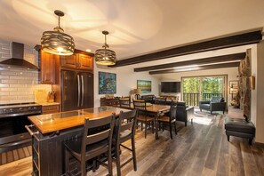 Cocina moderna con isla central, mesa de comedor de madera y sillas. Una ventana grande ofrece luz natural y vistas al exterior.