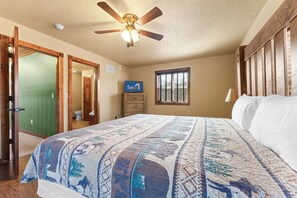 A bedroom with a large bed, a ceiling fan, a window, and a wooden headboard. - Exquisite Decor in this 6 BD Cabin! Super Close to Fun Attractions and Shops! (Branson West)