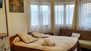Un dormitorio con una cama grande, un sofá y una ventana con cortinas.