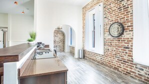 Een keuken met een bakstenen muur, een groot raam en een klok aan de muur.