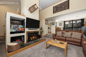 A living room with a fireplace, a television, a sofa, and a coffee table. - Crestview Place Unit 607 Spacious with mt views & private decks family friendly (Winter Park)