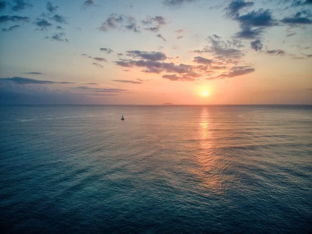 Mar tranquila al atardecer con un barco a lo lejos.