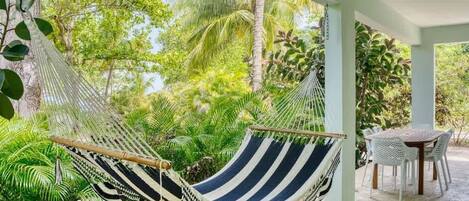Silla hamaca en un espacio exterior cubierto con vista a follaje tropical.