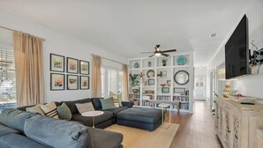 Uma sala de estar moderna com um sofá seccional, uma mesa de centro e uma estante repleta de objetos decorativos.