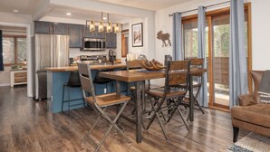 Een moderne keuken met een centraal eiland, houten stoelen en een eettafel.