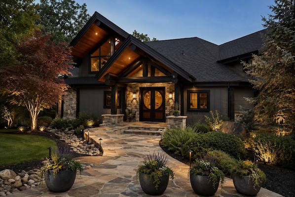 A modern house with a stone facade, large windows, and a well-lit entrance.
