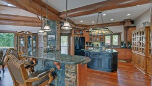 Una cocina amplia con una isla grande, armarios de madera y una pared de acento de piedra.