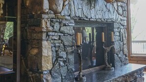 Una chimenea de piedra con diseño rústico, que incluye un repisa de troncos de madera y velas.