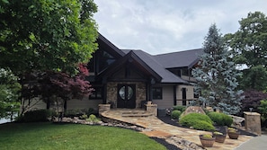A two-story house with a stone facade, a black front door, and a stone pathway leading to the entrance.