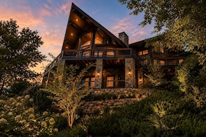 A multi-level cabin with stone exterior walls, multiple balconies, and a stone foundation.
