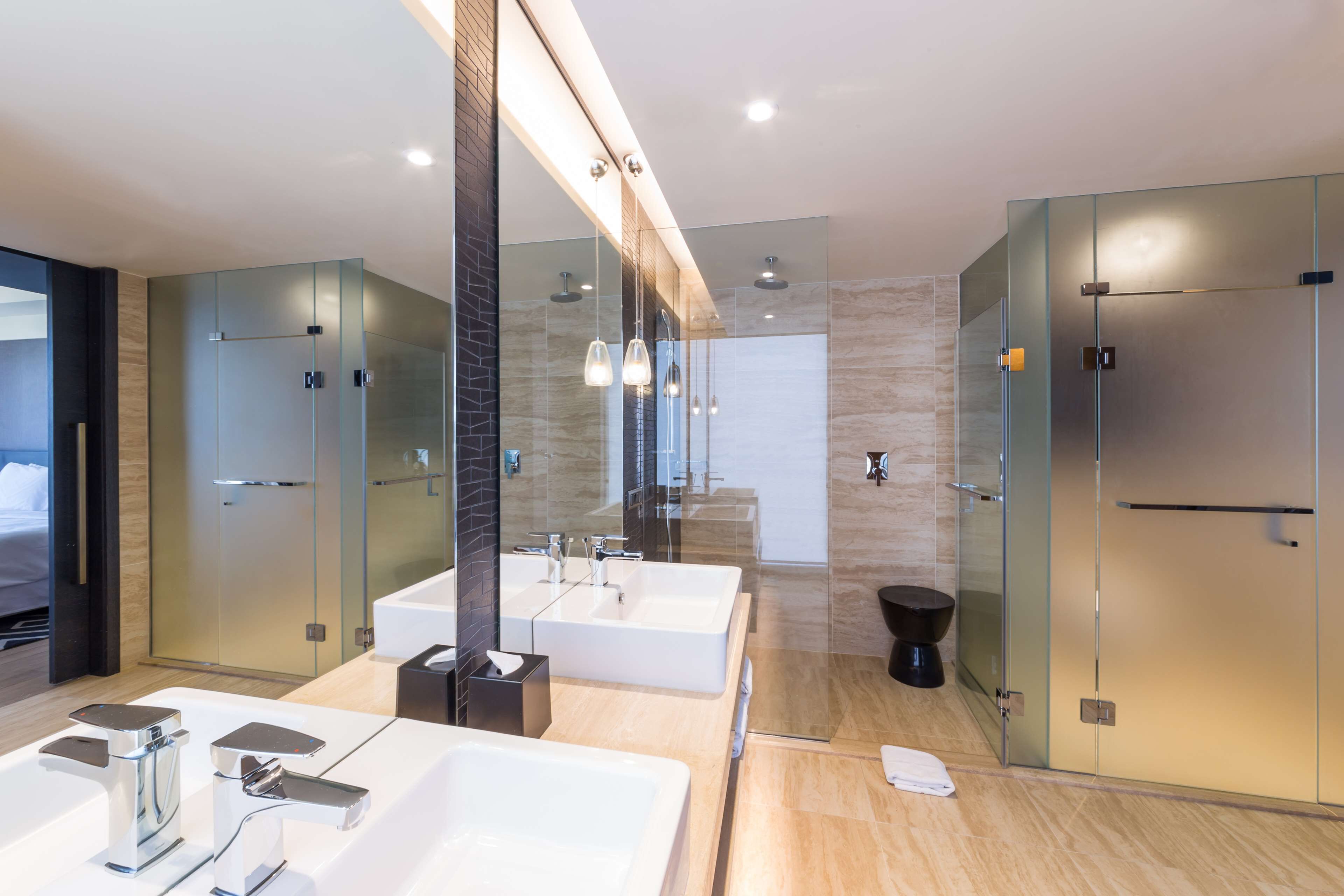 A modern bathroom with two sinks, a large mirror, and a glass shower enclosure.