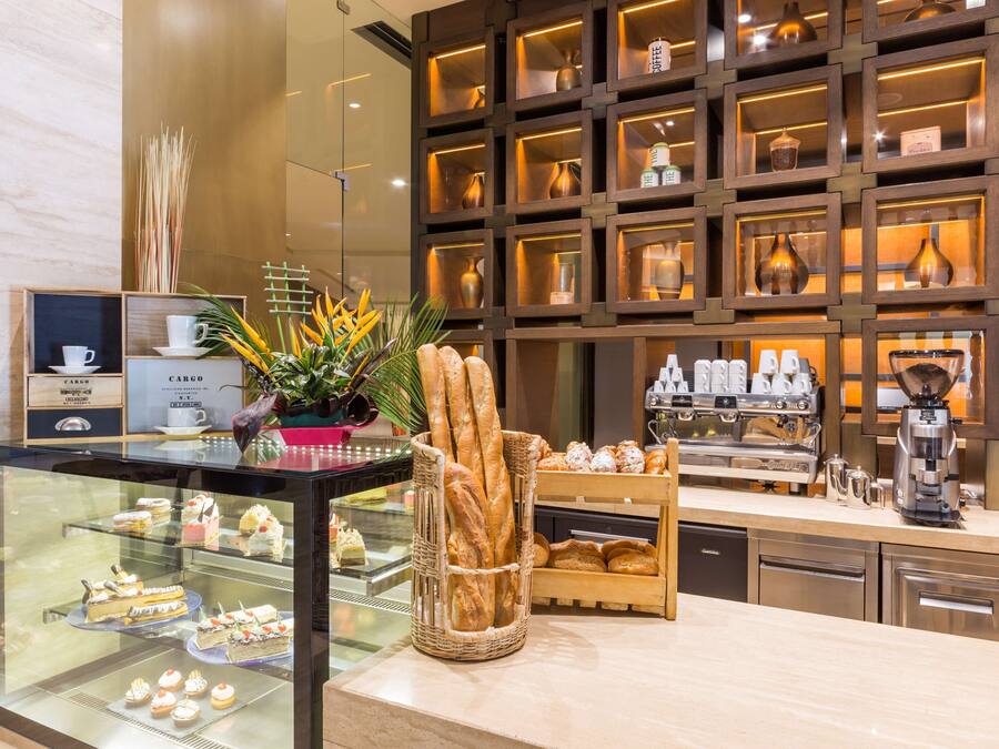 A bakery display with pastries and bread, a coffee machine, and a decorative plant.