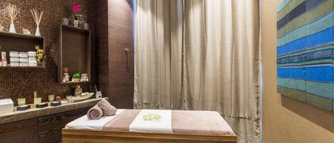 Un cuarto de spa con un banco de madera, un espejo, un estante con artículos de tocador y un tapiz grande en la pared.