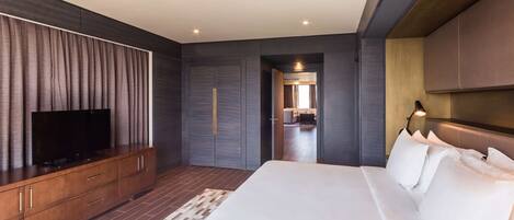 A modern hotel room with a large bed, a flat-screen TV on a wooden console, and a walk-in closet.