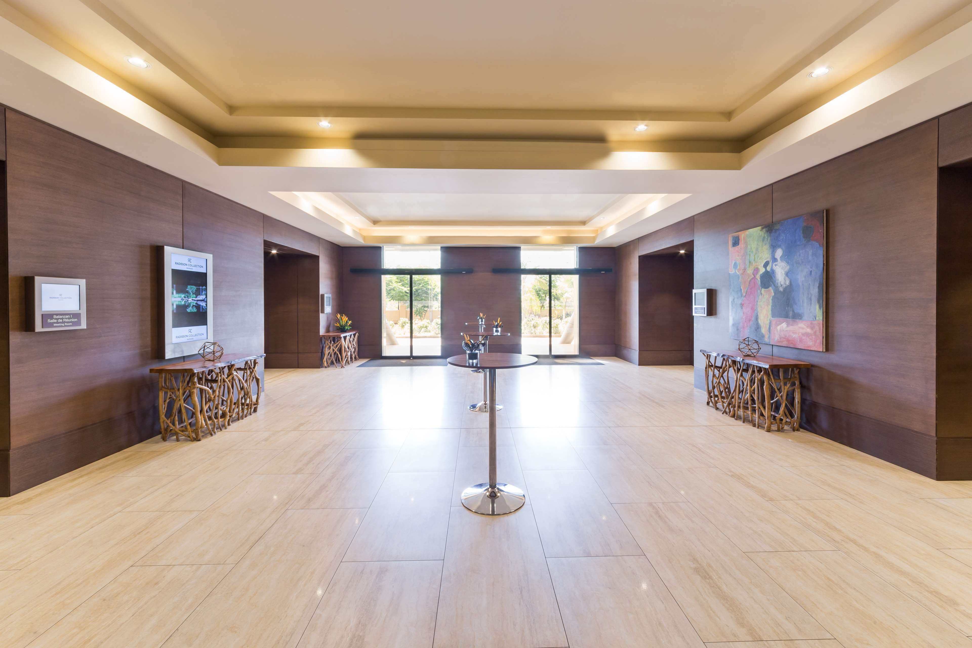 Un vestíbulo amplio con una mesa redonda central, paneles de madera y obras de arte en las paredes.