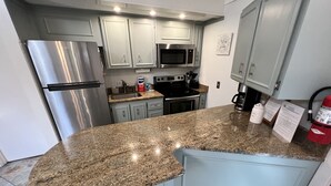 A modern kitchen with granite countertops, stainless steel appliances, and light gray cabinetry.