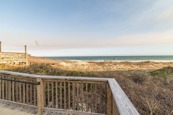A wooden boardwalk leading to a beach with a clear view of the ocean.