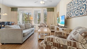 A living room with a sofa, armchair, coffee table, and a television.