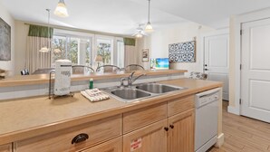 A modern kitchen with a double sink, wooden cabinets, and a dishwasher.