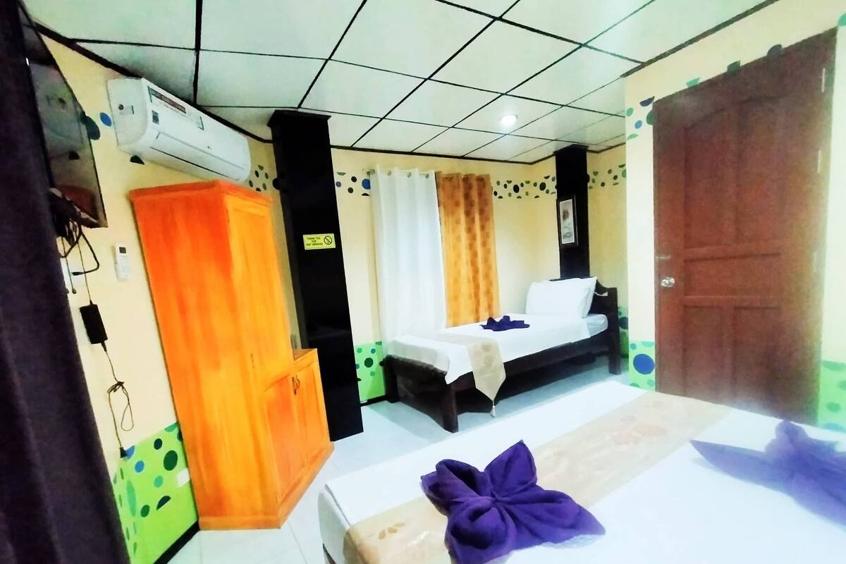 A hotel room with a bed, a wardrobe, and a small table.
