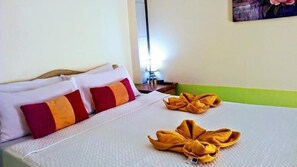 A hotel room with a neatly made bed, pillows, and towels. - Hwan Dynasty Suite Elnido (El Nido)