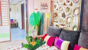 A room with a sofa, a potted plant, and a wall with circular cutouts. - Hwan Dynasty Suite Elnido (El Nido)