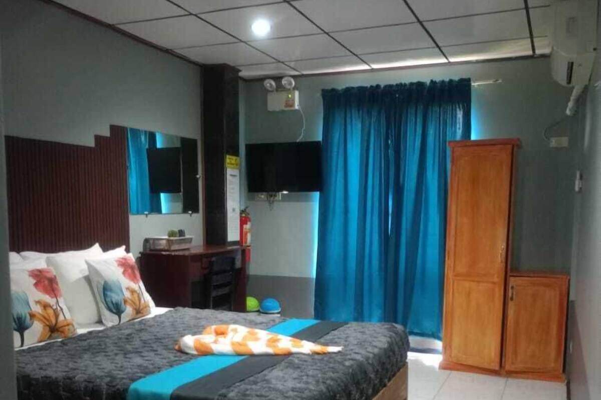 A bedroom with a bed, a desk, a wardrobe, and a television.