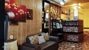 A cozy room with a wooden wall, a sofa with patterned cushions, a decorative shelf with various items, and a patterned floor. - Hwan Dynasty Suite Elnido (El Nido)