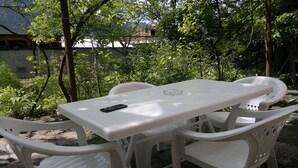 A white plastic table and chairs set outdoors with a smartphone on the table. - Guest House Besarioni (Borjomi)