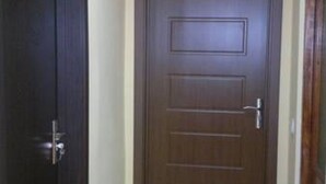 A hallway with a wooden door and a closed door on the left. - Guest House Besarioni (Borjomi)