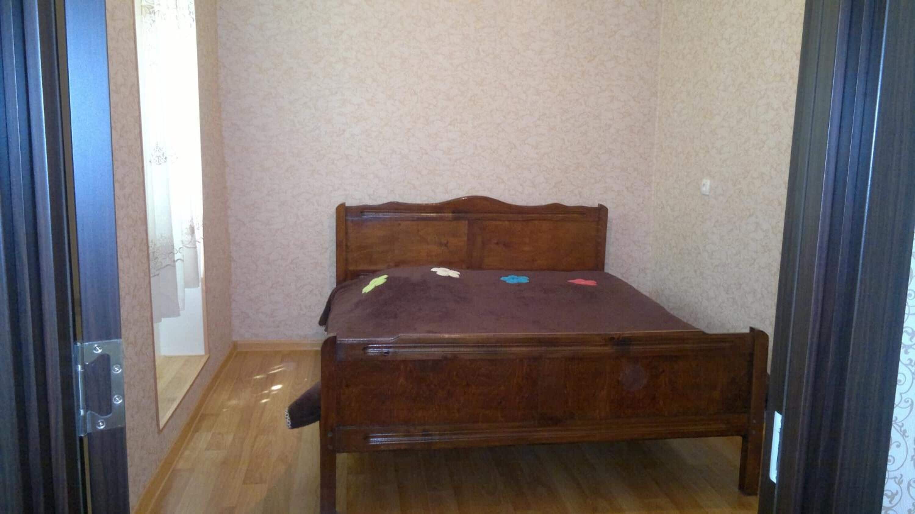 A small, single-bed room with a wooden headboard and a brown bedspread.