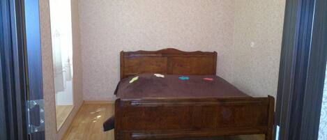 Una habitación pequeña con una cama individual, cabecera de madera y colcha marrón.