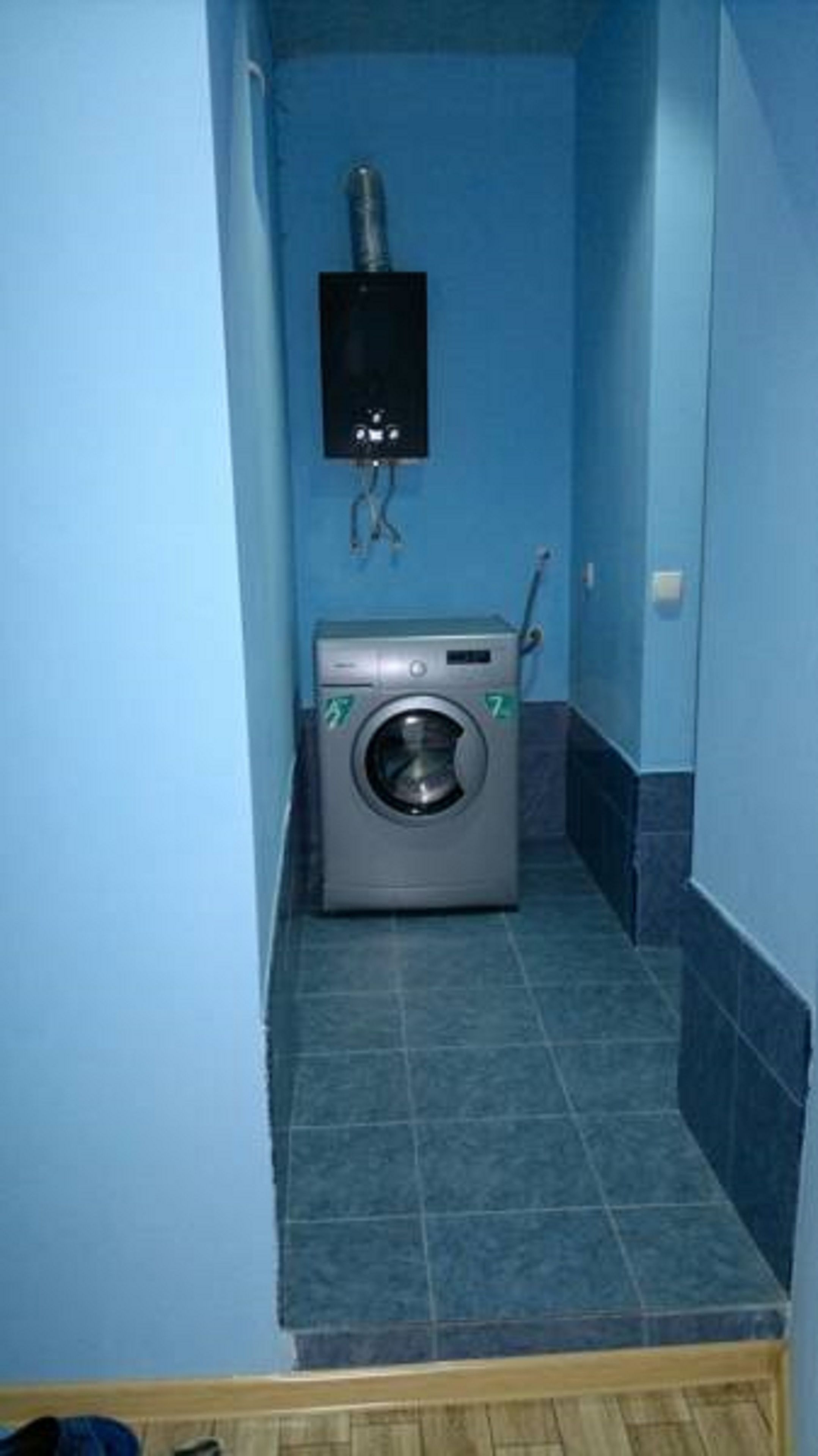 Une petite buanderie équipée d’un lave-linge, d’un sèche-linge et d’un système de ventilation fixé au mur.