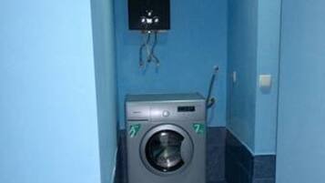 Une petite buanderie équipée d’un lave-linge, d’un sèche-linge et d’un système de ventilation fixé au mur.